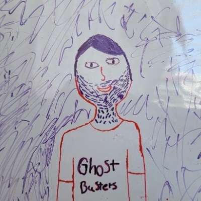 a child's drawing of me as line-art. i have a boring man head and stubble, with assymetrical features, and am wearing a ghostbusters t-shirt.